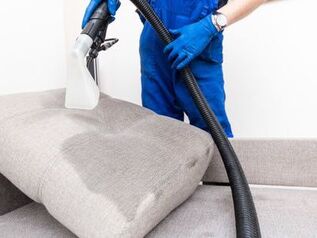 A man cleaning a sofa and upholstery with a steam cleaner